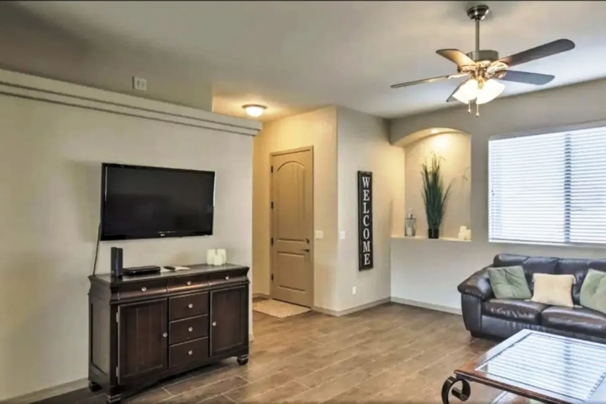 A close-up view of a cozy living nook with a comfortable sofa, a television, a welcoming decorative 'WELCOME' sign, and a leafy plant. The inviting setup encourages relaxing, watching TV, or sharing time with family and friends.