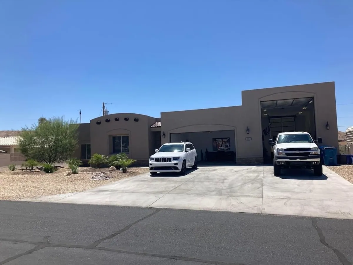 The front driveway is pictured with two vehicles parked, surrounded by a landscaped area. The inviting atmosphere hints at family comings and goings, as well as the convenience of launching into nearby waterfront adventures.