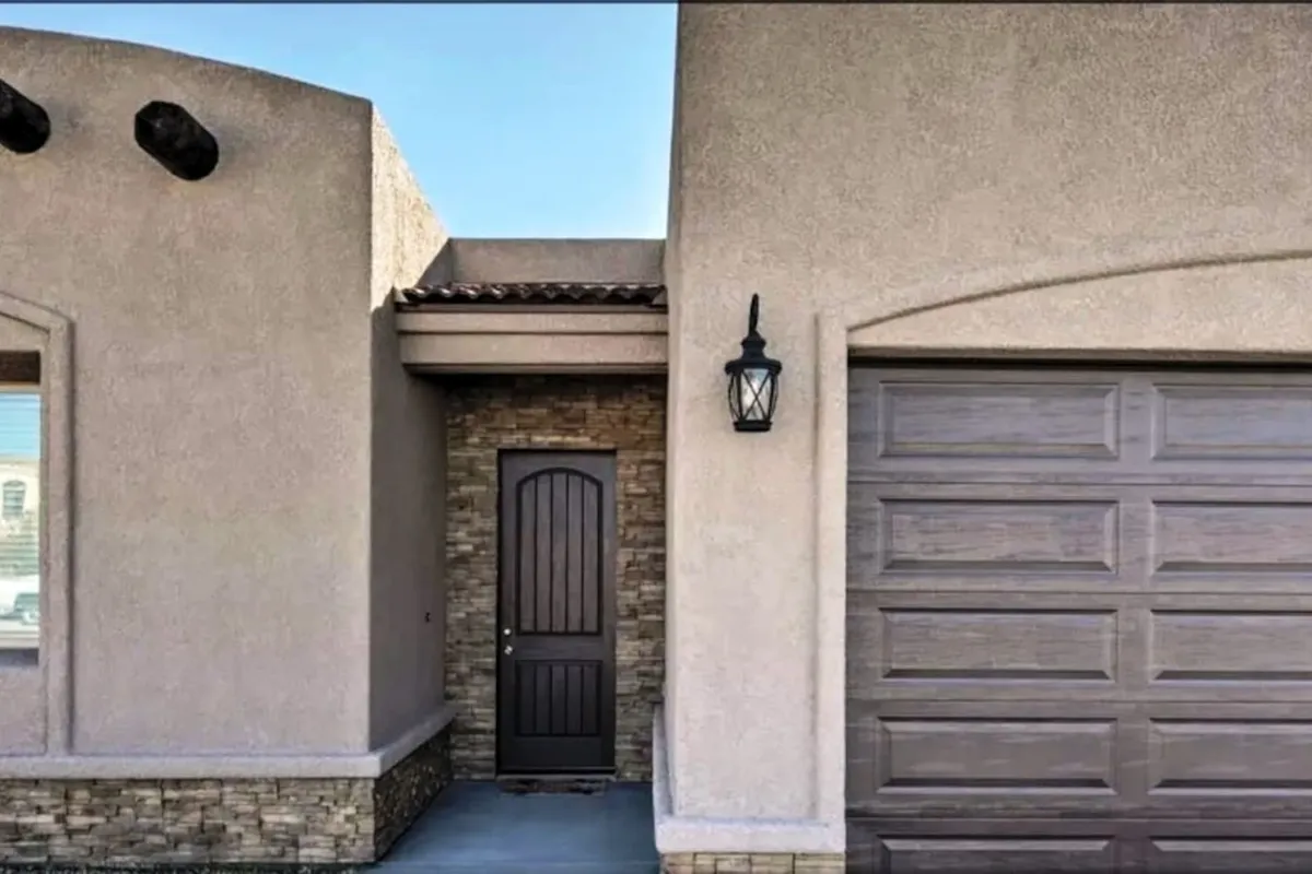 This exterior shot features an arched wooden front door framed by a stone accent wall and a decorative lantern, creating a welcoming, inviting entrance. The scene evokes a sense of arrival and anticipation before heading out to explore the lively local scene.